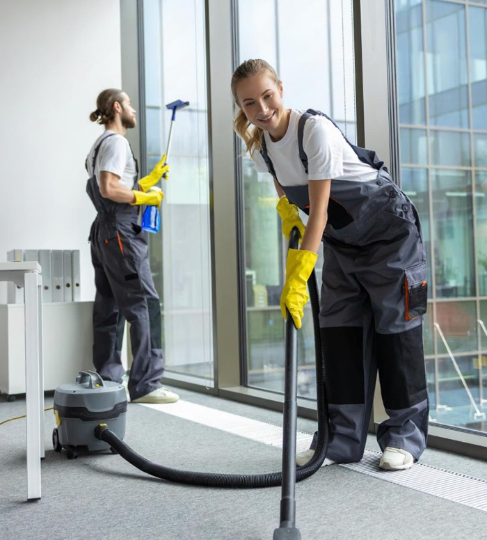 Two commercial cleaners vacuuming and cleaning the windows of an office