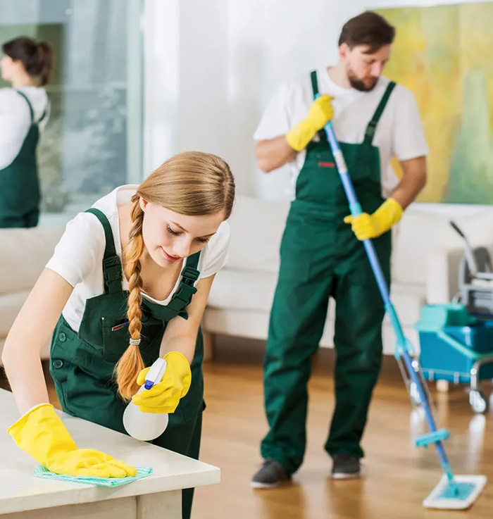 Two cleaners wiping a bench and mopping the floor of a living room